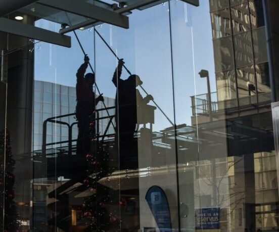 utility man standing in scissor platform cleaning glass window